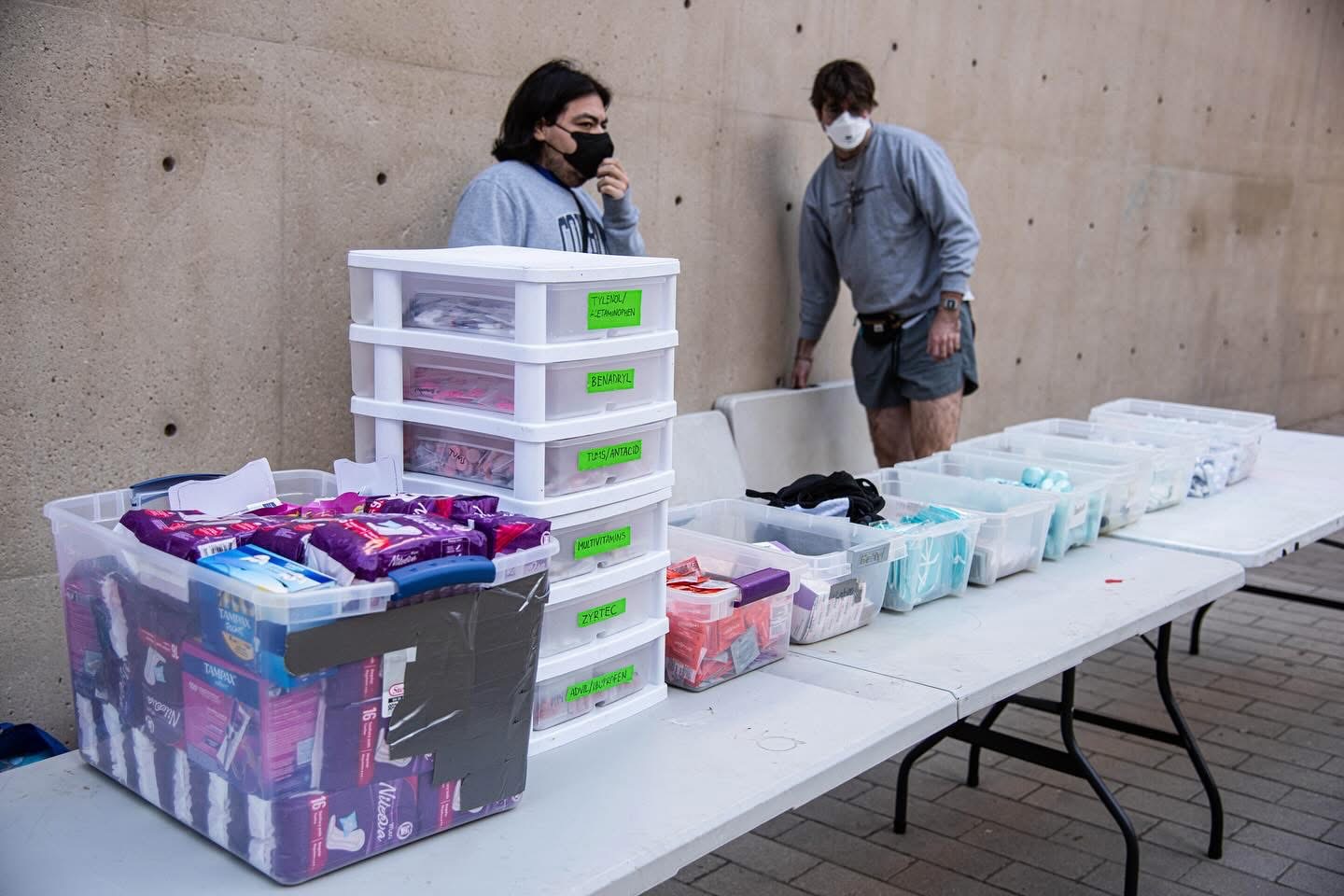 Labeled bins of medicine and hygiene supplies on distribution tables