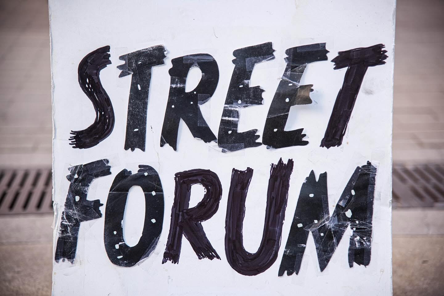 Hand-lettered Street Forum sign taped to a board